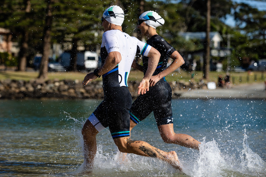 Man and woman running in the EVO tri suits in the shallow sea water