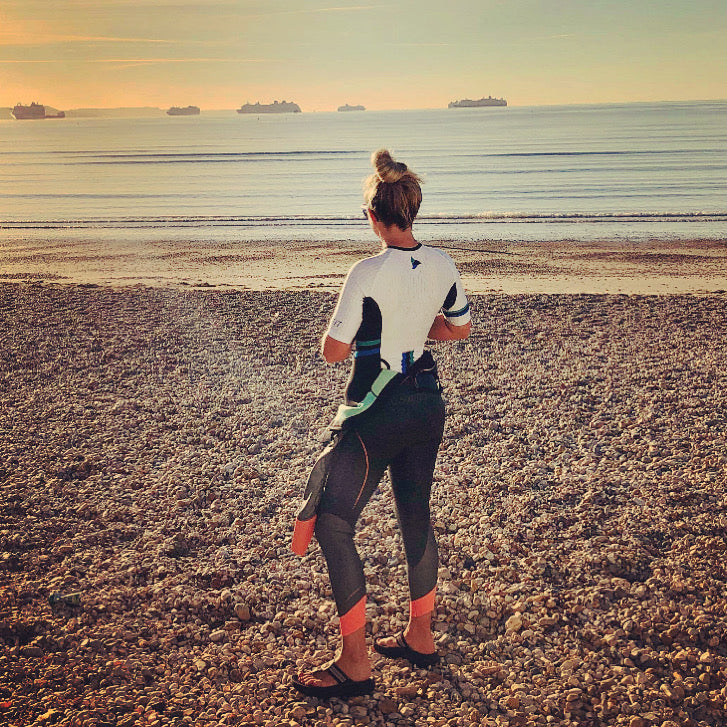 Woman wearing the EVO women's tri suit standing on a sandy beach