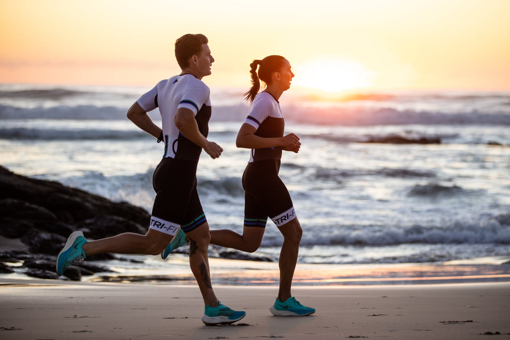 man and woman running along the beach wearing the evo tri suit