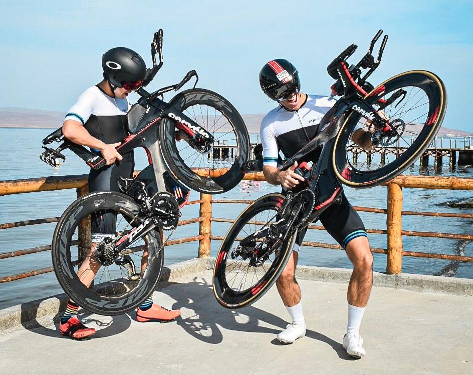 Two men holding up their bikes wearing the EVO mens tri suit